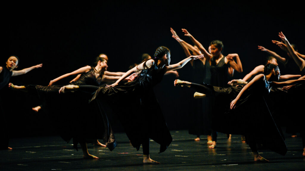 Spectacle de danse contemporaine, groupe de danseuses en robes noires sur scène