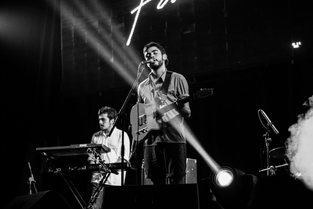 Guitariste et claviériste sur scène lors d'un concert, éclairage en noir et blanc