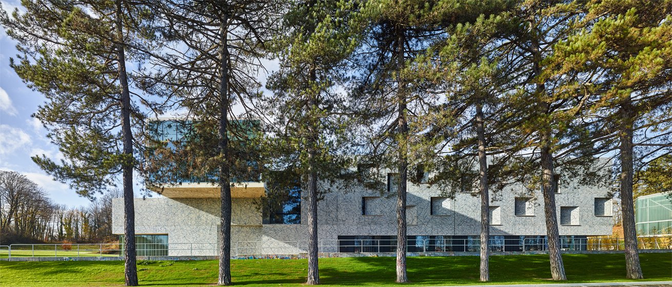 Façade extérieure du Conservatoire Henri Dutilleux vue depuis le parc, entourée de grands pins